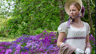 woman in historical colonial period dress walking in the fields