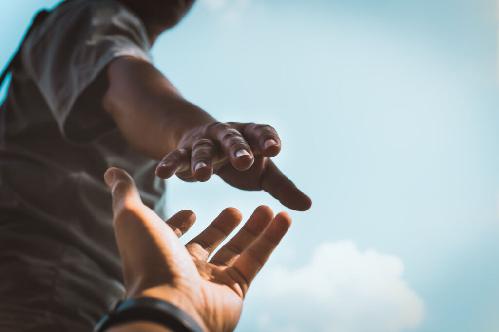 Help Concept hands reaching out to help each other in dark tone.