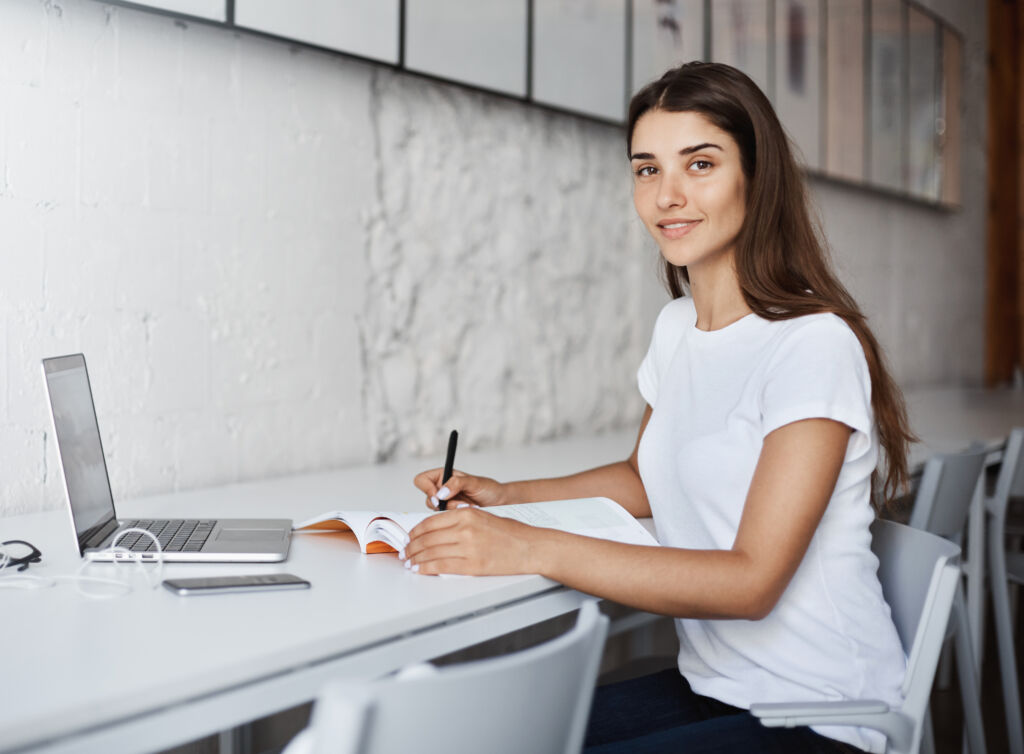 Young caucasian lady student looking at camera smiling learning furniture design book. Education concept.