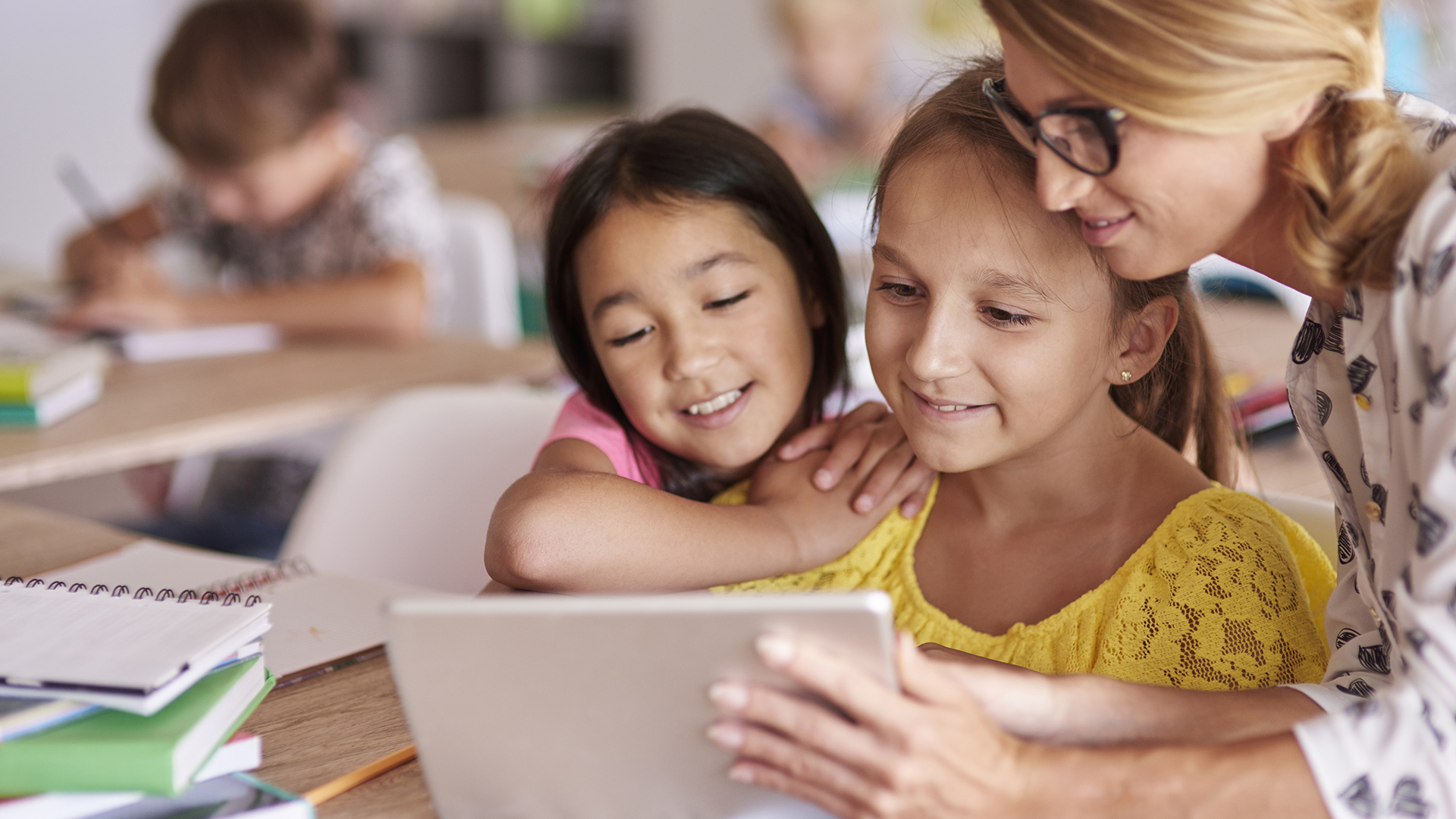 Teacher helping pupils with digital tablet